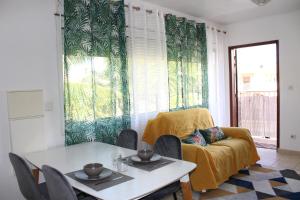 - un salon avec une table et un canapé jaune dans l'établissement L'hibiscus - Proche centre de Cayenne, à Cayenne