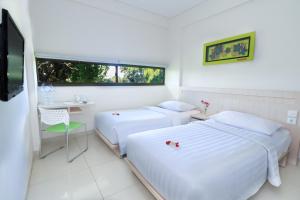 a bedroom with two beds and a desk and a television at J Hotel Kuta in Kuta