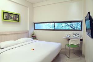 Schlafzimmer mit einem Bett, einem Schreibtisch und einem Fenster in der Unterkunft J Hotel Kuta in Kuta