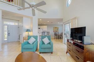 a living room with two blue chairs and a flat screen tv at Waterfront Haven Retreat in Destin