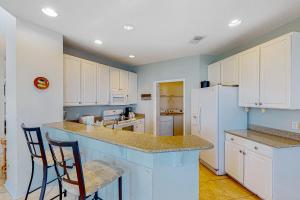uma cozinha com paredes azuis e armários e balcões brancos em Waterfront Haven Retreat em Destin