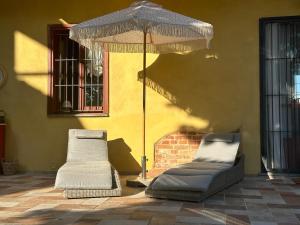 dos camas sentadas bajo una sombrilla junto a un edificio en Casale di Anna, en Piea