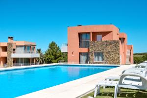 a villa with a swimming pool in front of a building at Lomas del Real Apart in Colonia del Sacramento