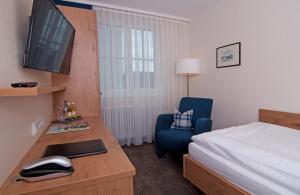 a hotel room with a desk with a computer and a bed at Gasthof Landhotel Hirsch in Ostrach