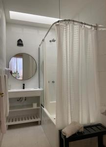 Baño blanco con cortina de ducha y lavamanos en V&S Hostel Boutique en Buenos Aires
