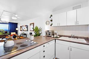 Kahana Villa F407 في Kapalua-West Maui Airport: مطبخ بخزائن بيضاء وطاولة عمل