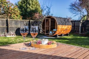 dois copos de vinho numa mesa de madeira com um barril de madeira em Allen Street - Studio & Optional Private Sauna em Methven