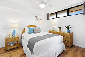 a white bedroom with a bed and two night stands at Kahana Villa F407 in Kahana +9 photos