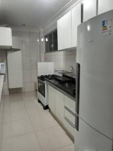 a white kitchen with a stove and a refrigerator at Apartamento setor Bueno in Goiânia