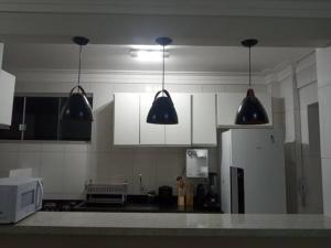 a kitchen with white cabinets and black pendant lights at Apartamento setor Bueno in Goiânia