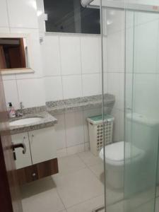 uma casa de banho com um WC e uma cabina de duche em vidro. em Apartamento setor Bueno em Goiânia