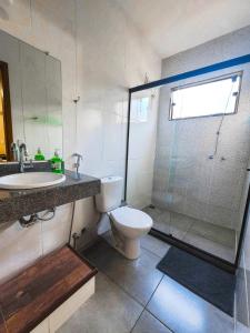 a bathroom with a toilet and a sink and a shower at Villa Terracotta in Miguel Pereira