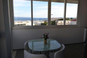 a glass table with two white chairs and a vase with flowers at Apartments Kike&Ana in Split