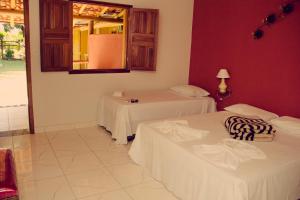 Habitación con 2 camas y espejo en la pared. en Hotel Fazenda Coninho en Inhaúma