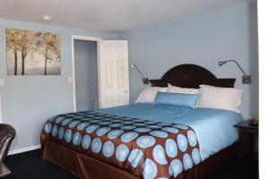 a bedroom with a large bed with a blue blanket at Hitching Post Motel 