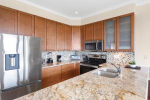 eine Küche mit Holzschränken und einem Edelstahlkühlschrank in der Unterkunft Kapalua Golf Villa 18V4 in Kahana