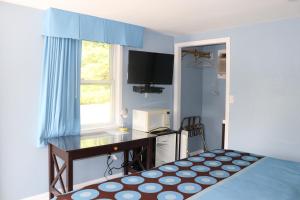 a bedroom with a desk and a bed with a window at Hitching Post Motel 
