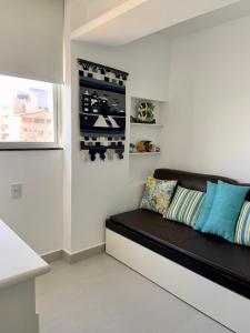 a black couch in a white room with a window at Apartamento vista do mar, pé na areia e águas tranquilas, no cento de Guarapari in Guarapari