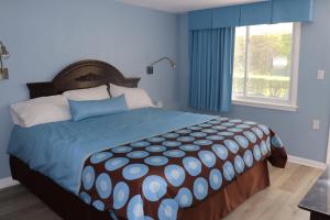 a bedroom with a large bed with blue walls and a window at Hitching Post Motel 
