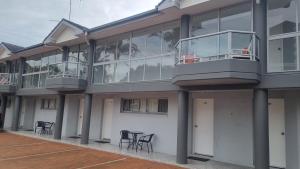 a building with a balcony with tables and chairs at Forstay Motel in Forster