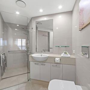a white bathroom with a sink and a shower at Costa Nova Holiday Apartments in Sunshine Beach