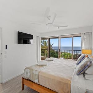 a white bedroom with a bed and a large window at Costa Nova Holiday Apartments in Sunshine Beach