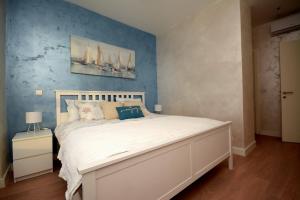 a bedroom with a white bed with a blue wall at GIGI Apartment in Belgrade +27 photos