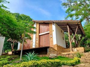 une maison avec une porte en bois dans un jardin dans l'établissement Estancia Arboreto - Reserva Natural, à Barichara