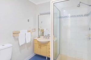 a bathroom with a shower and a toilet and a sink at Reflections Hawks Nest - Holiday Park in Hawks Nest