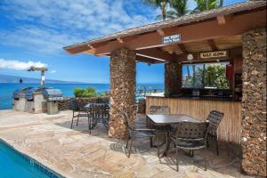 um pátio com uma mesa e cadeiras ao lado de uma piscina em Noelani 208 em Kahana