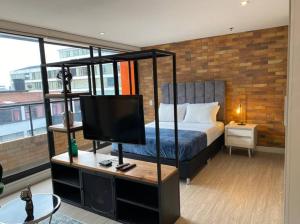 Schlafzimmer mit einem Bett und einem TV auf einem Schreibtisch in der Unterkunft 512 Sleek Haven Loft in Bogotá