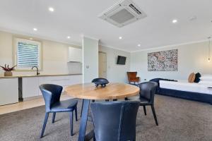 a room with a table and chairs and a bed at Central Caleula Motor Lodge in Orange