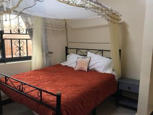 - une chambre avec un lit à baldaquin et une fenêtre dans l'établissement Amazing lake Victoria Villa, Entebbe, à Entebbe