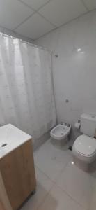 een witte badkamer met een toilet en een wastafel bij Departamentos Solares - O'Higgins in Bahía Blanca