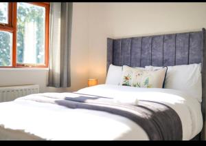 een slaapkamer met 2 witte bedden met een grijs hoofdeinde bij House of Kaima - 6 bed detached in Dewsbury