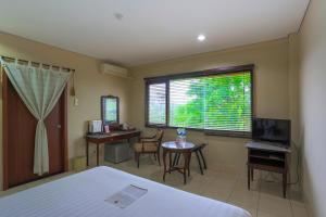 Schlafzimmer mit einem Bett, einem Schreibtisch und einem Fenster in der Unterkunft The Jayakarta Suites Komodo Flores in Labuan Bajo