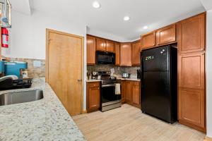 a kitchen with a black refrigerator and wooden cabinets at Comfy Family-Friendly Getaway less than 15 mins to Downtown in Detroit