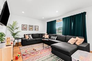 uma sala de estar com um sofá preto e cortinas verdes em Comfy Family-Friendly Getaway less than 15 mins to Downtown em Detroit
