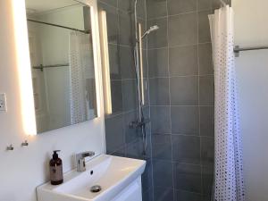 a bathroom with a sink and a shower with a mirror at Holiday home Jægerspris XVII in Jægerspris