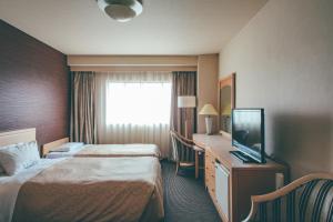 a hotel room with two beds and a flat screen tv at Numazu River Side Hotel in Numazu