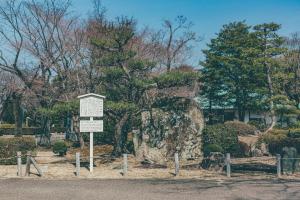 a sign in front of a tree and a rock at Kuretake Inn Nagoya Hisayaodori in Nagoya