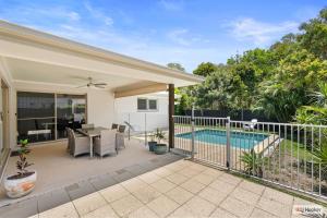 a patio with a table and chairs and a swimming pool at Casa Palmera in Casuarina