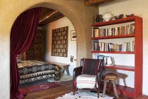 a bedroom with a bed and a book shelf with books at Casa Gallina - An Artisan Inn in Taos