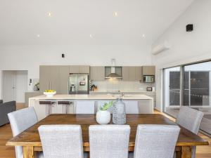 Una cocina y un comedor con mesa y sillas de madera. en Casuarina Surfbreak Beach House with Pool, en Casuarina