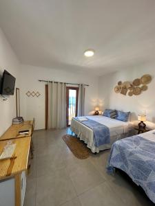 a bedroom with two beds and a television in it at Villa Dom Felippe in Jericoacoara