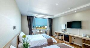 um quarto de hotel com uma cama e uma televisão de ecrã plano em Jeju In Hotel em Jeju