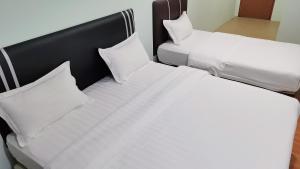 2 łóżka w pokoju z białą pościelą i poduszkami w obiekcie Salim Room w mieście Sibu