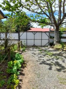 une clôture avec un arbre devant une maison dans l'établissement Agradable Cabaña campestre a 7 minutos de Osorno, à Osorno