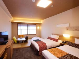 una camera d'albergo con due letti e una televisione di Kyoto Hot Spring Hatoya Zuihokaku Hotel a Kyoto