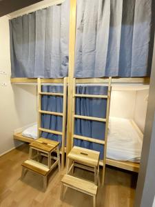 two bunk beds with two stools in a room at Dante House in Busan